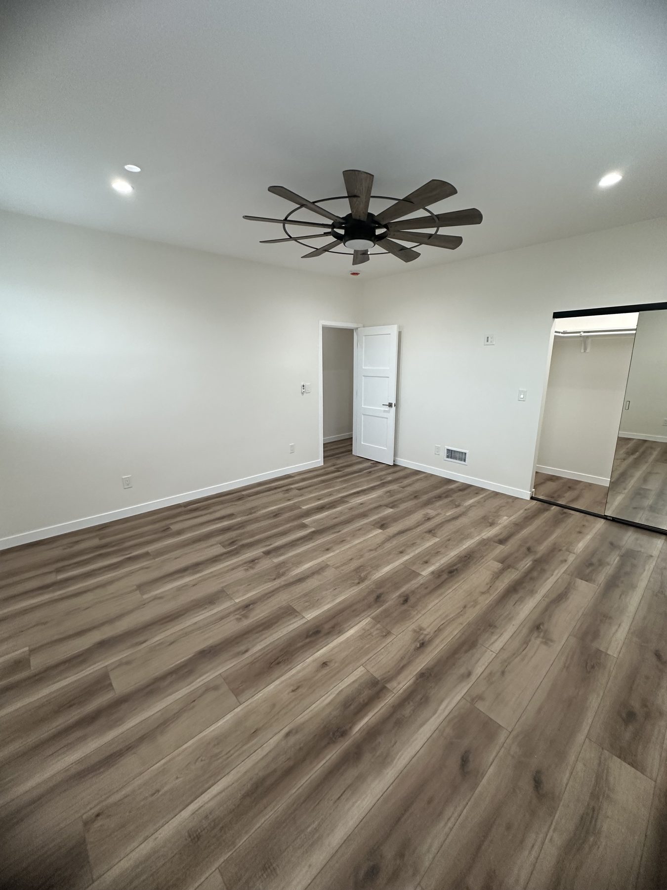 Bedroom with ceiling fan and mirrored sliding closet at 1148 S Rimpau Blvd