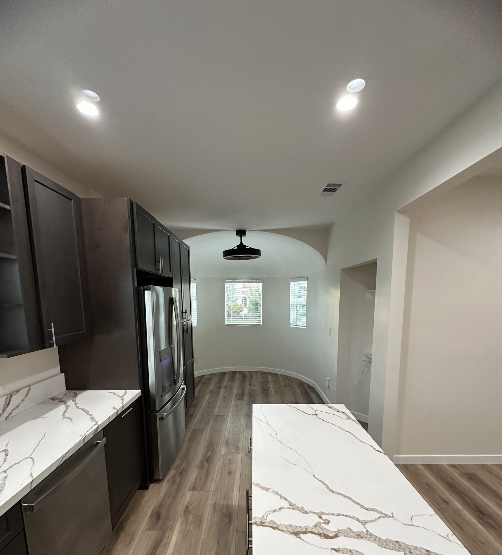 Kitchen with quartz island looking toward a rounded breakfast nook with windows