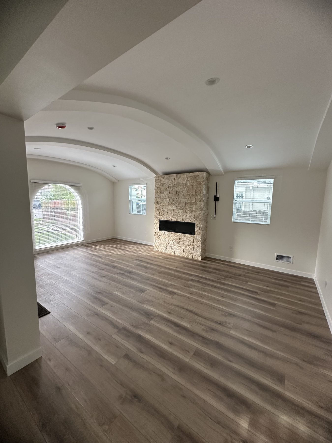 Living room with stone fireplace and arched ceiling at 1148 S Rimpau Blvd